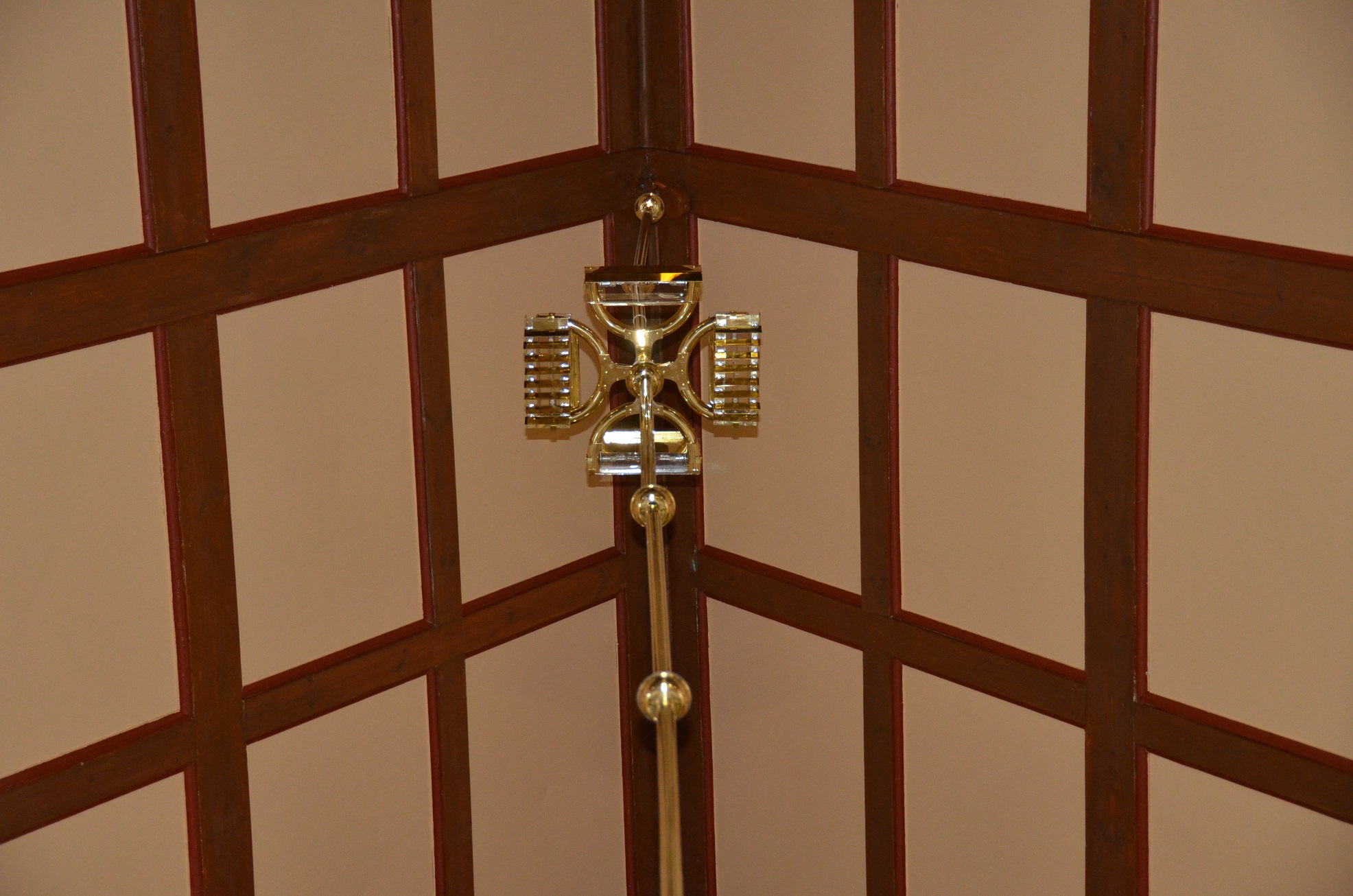 Förstärkningsljus monterad på pendelstång över ljuskronor i Järsnäs kyrka.